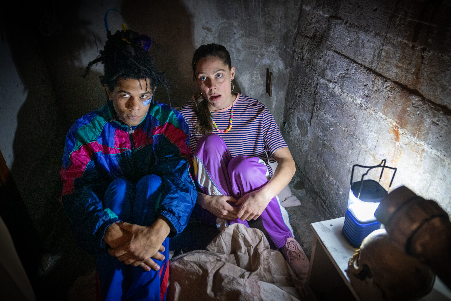 En mann og en kvinne som sitter på gulvet i en mørk kjeller