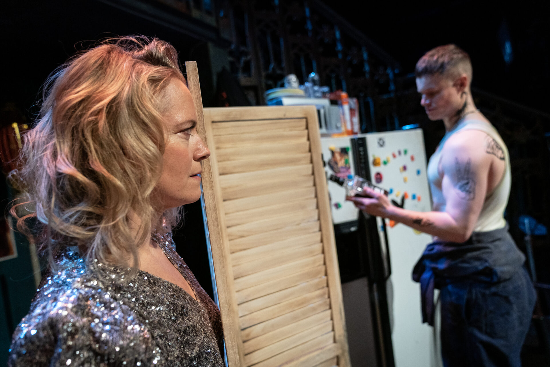 En kvinne betrakter en mann som står med en whiskeyflaske i hånden.