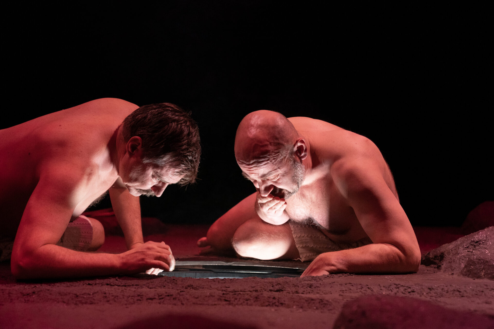 To nakne menn ser ned i et hull