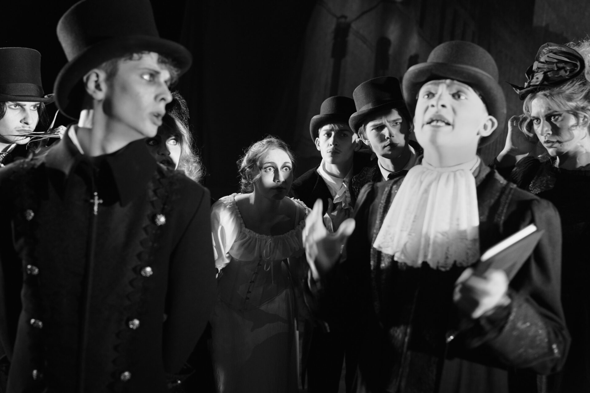 En gruppe kvinner og menn hører etter en mann med hatt og bok i hånda