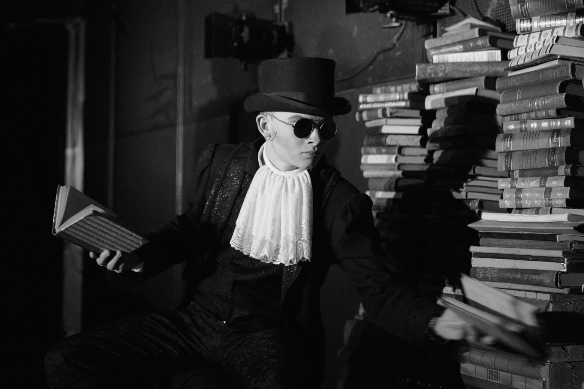 En mann sitter med en bok i hånden og leter etter en annen bok i en bokstakk