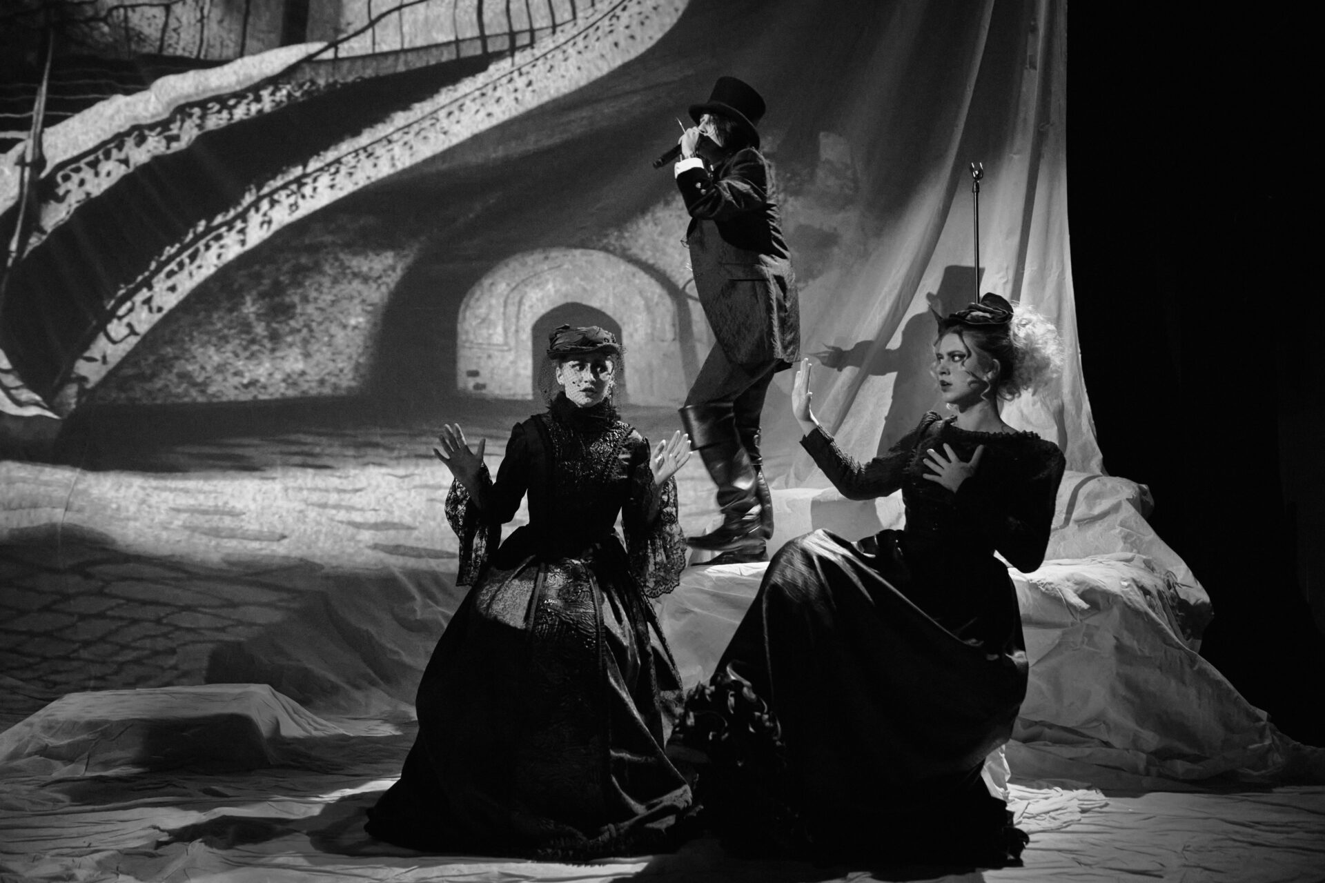 To kvinner sitter på stoler foran en mann med en mikrofon