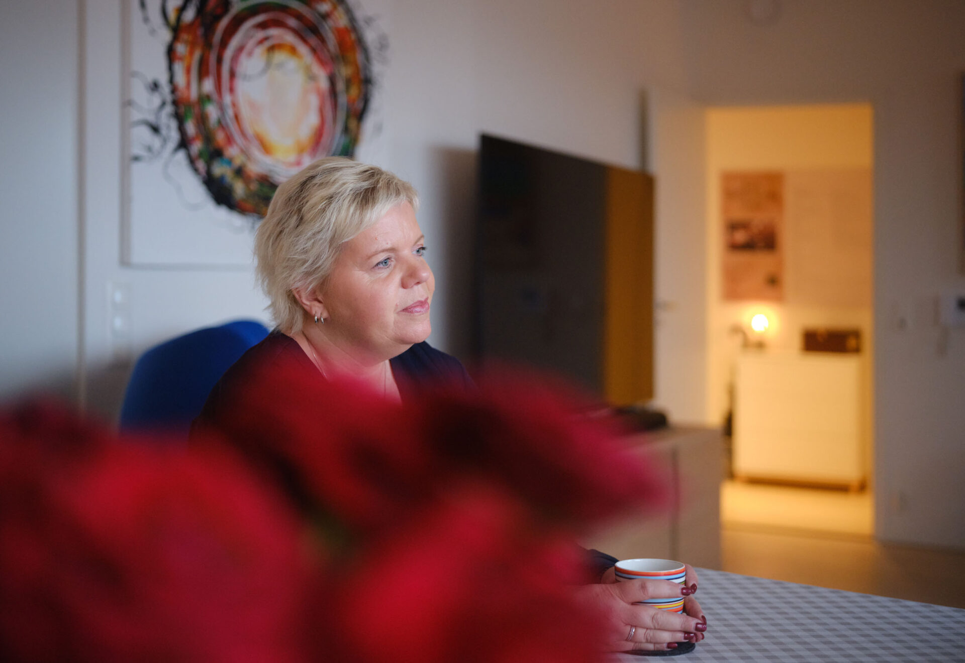 En kvinne sitter med sin kopp kaffe ved et spisebord