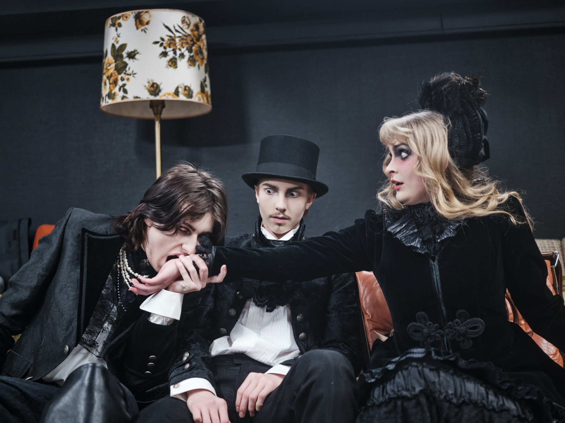 En ung mann er i ferd med å bite en kvinne i håndleddet. En annen mann ser bekymret på.