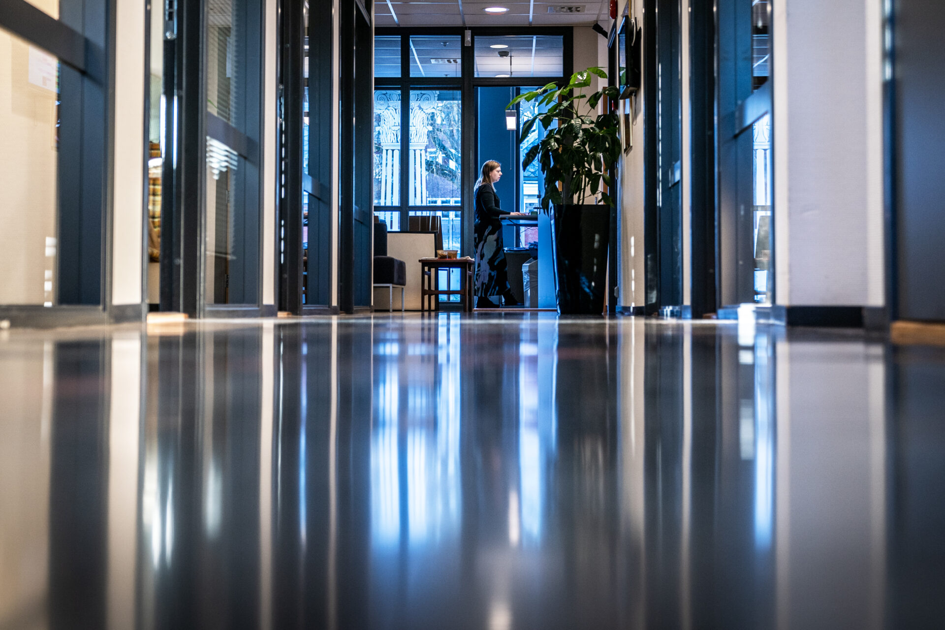 En kvinne står og arbeider ved sin PC.