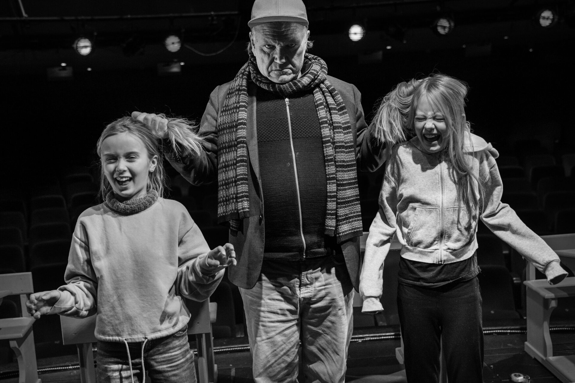 En mann holder to jenter i flettene