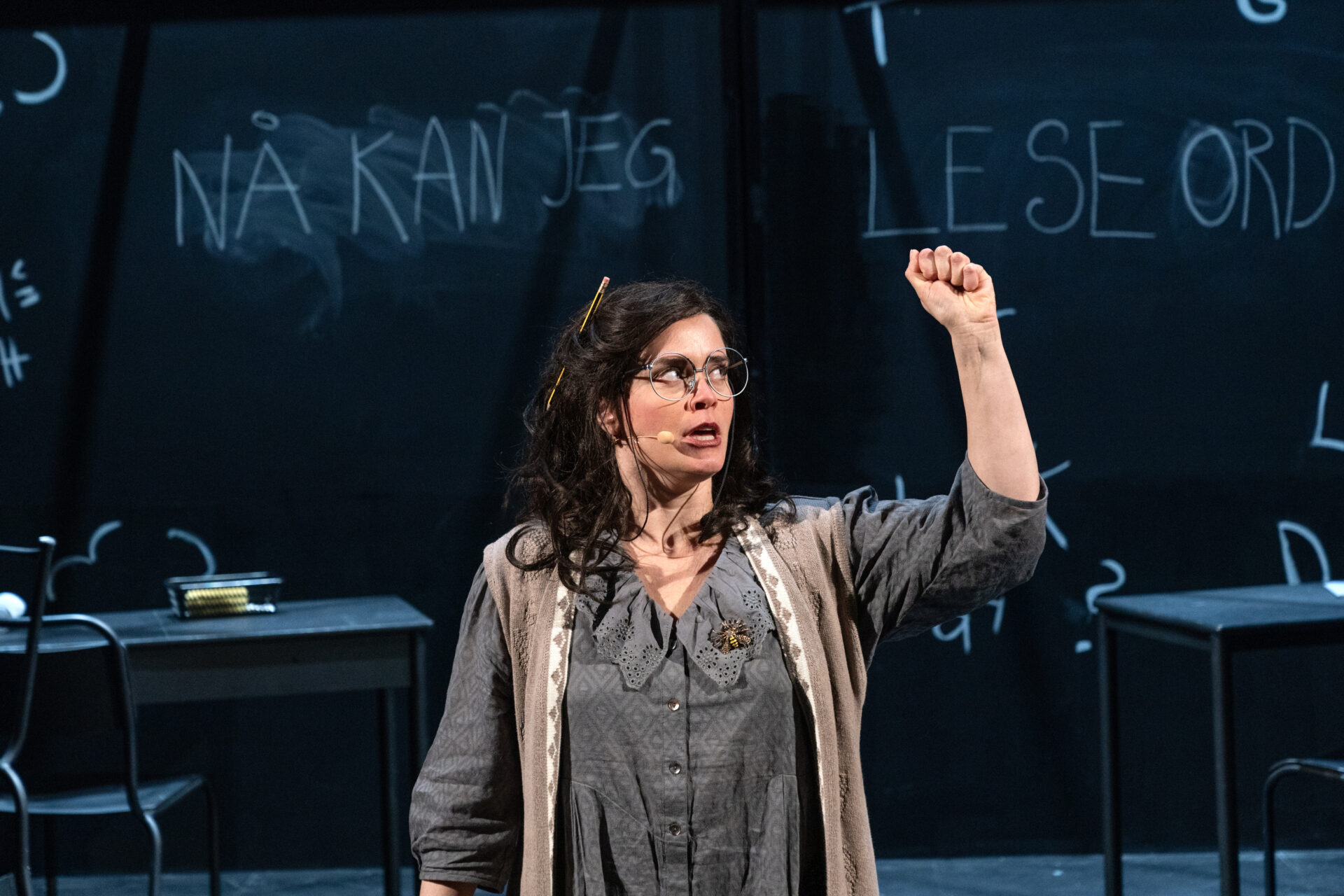 En lærer står foran en tavle med knyttet hånd