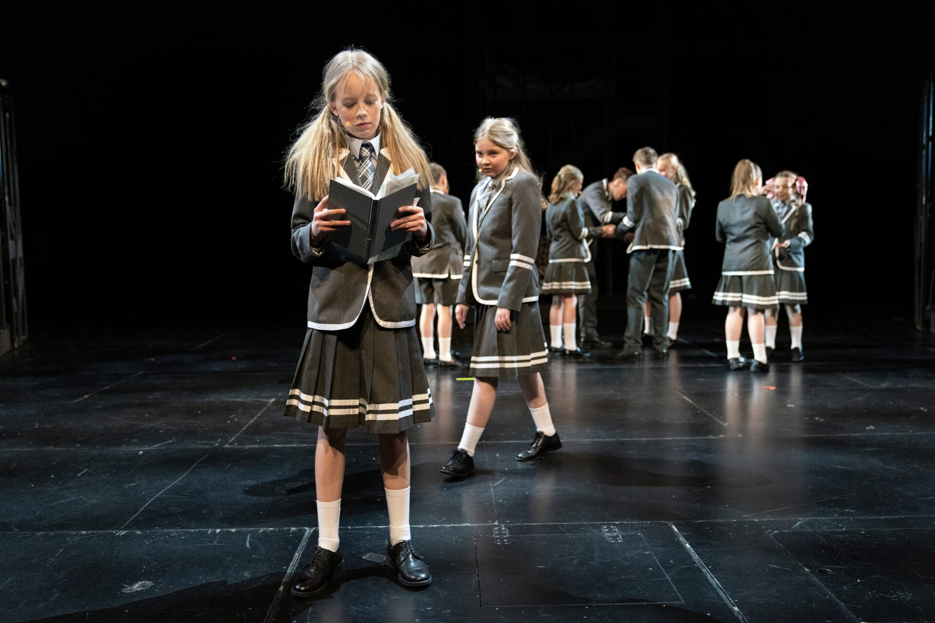 En jente leser i en bok og en liten jente nærmer seg henne bakfra