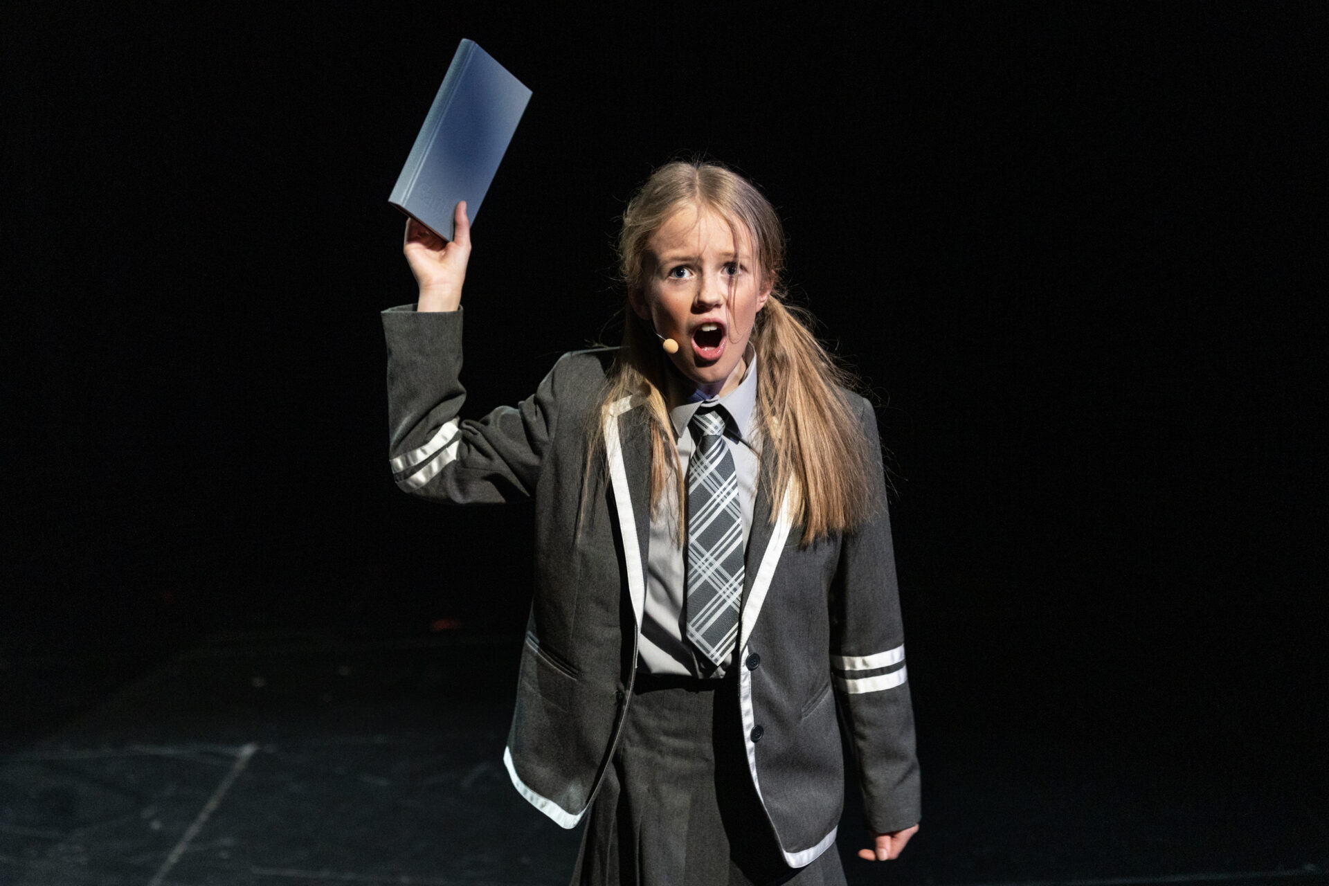 En pike står med en bok i hånden