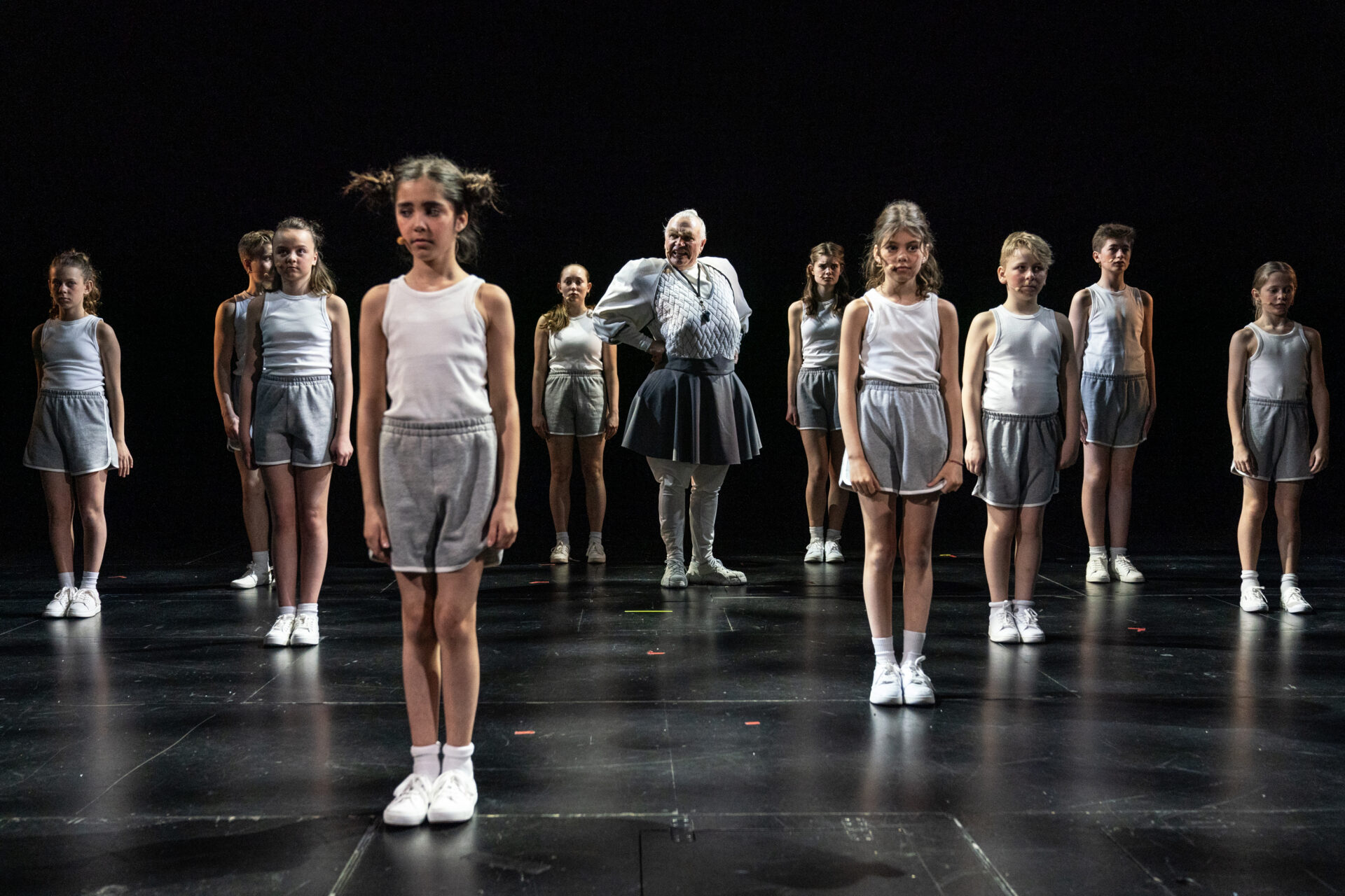 Mange barn står i giv akt i en gymtime, mens rektoren gir ordrer