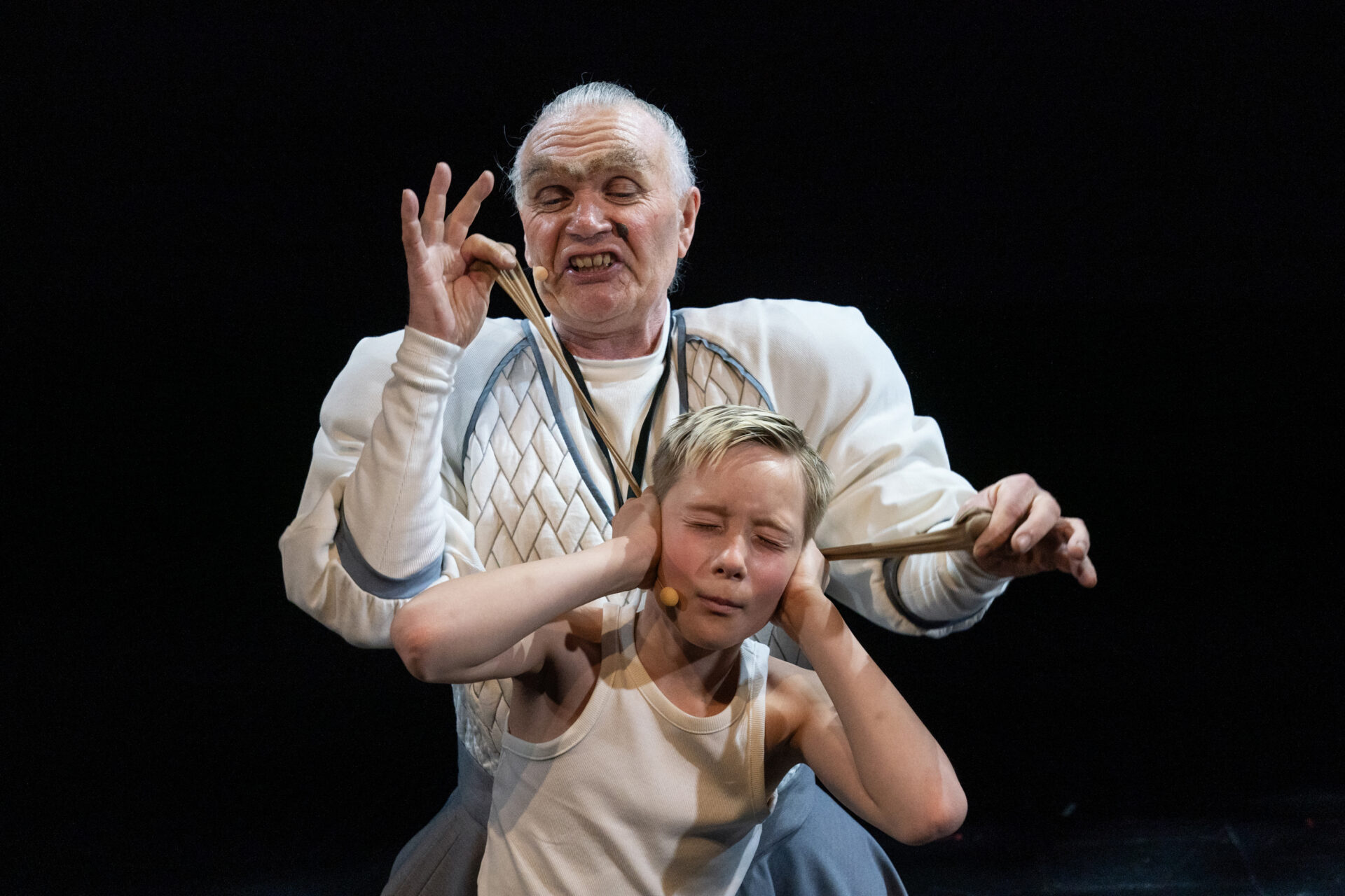 En kvinne drar en liten gutt i ørene