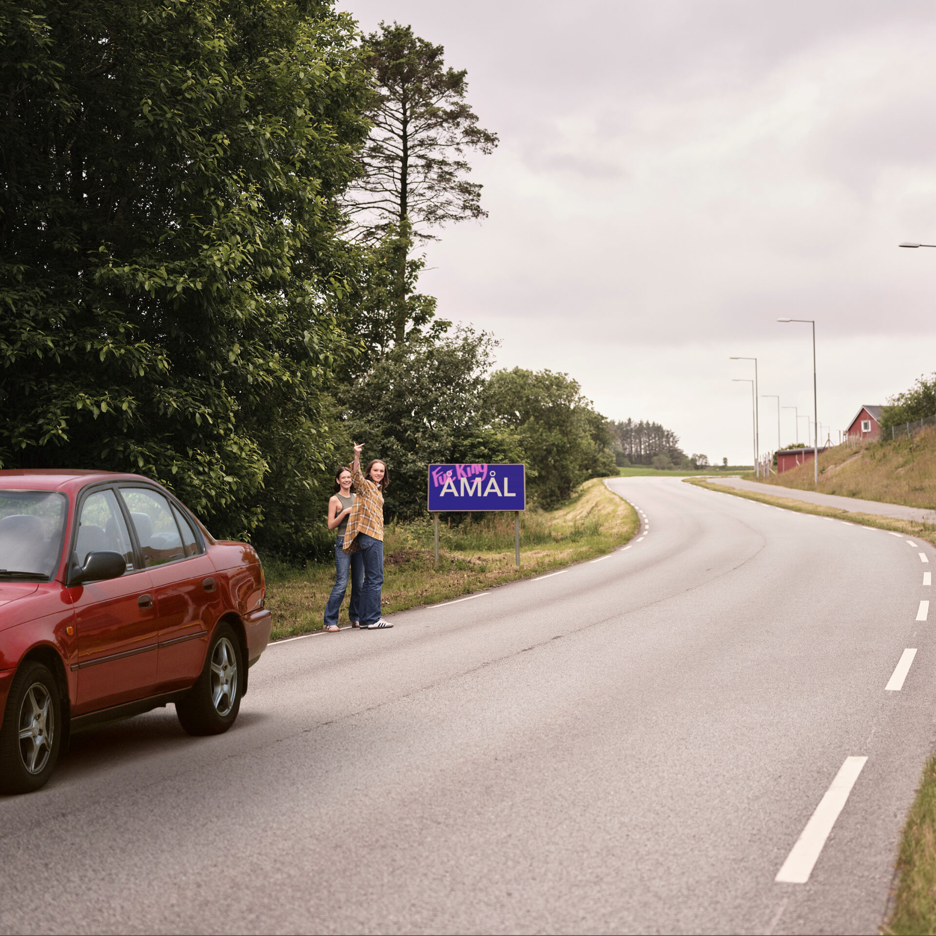 To jenter som står i veikanten og haiker