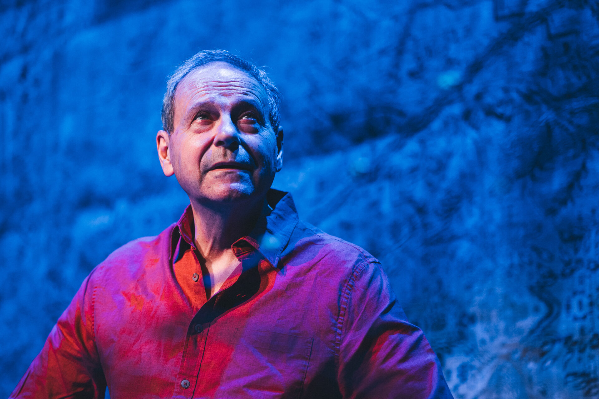 En mann i rød skjorte på scenen, som titter oppover