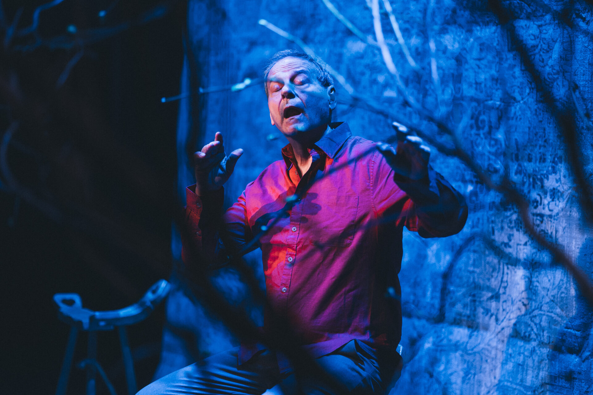 En mann som sitter på en krakk på scenen og formidler