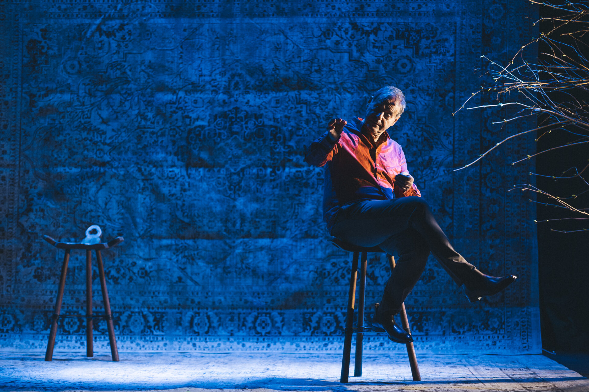 En mann som sitter på en krakk på scenen