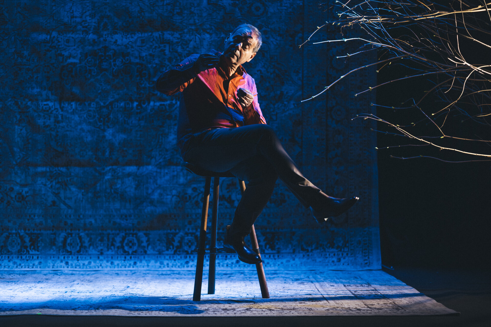 En mann som sitter på en krakk på scenen