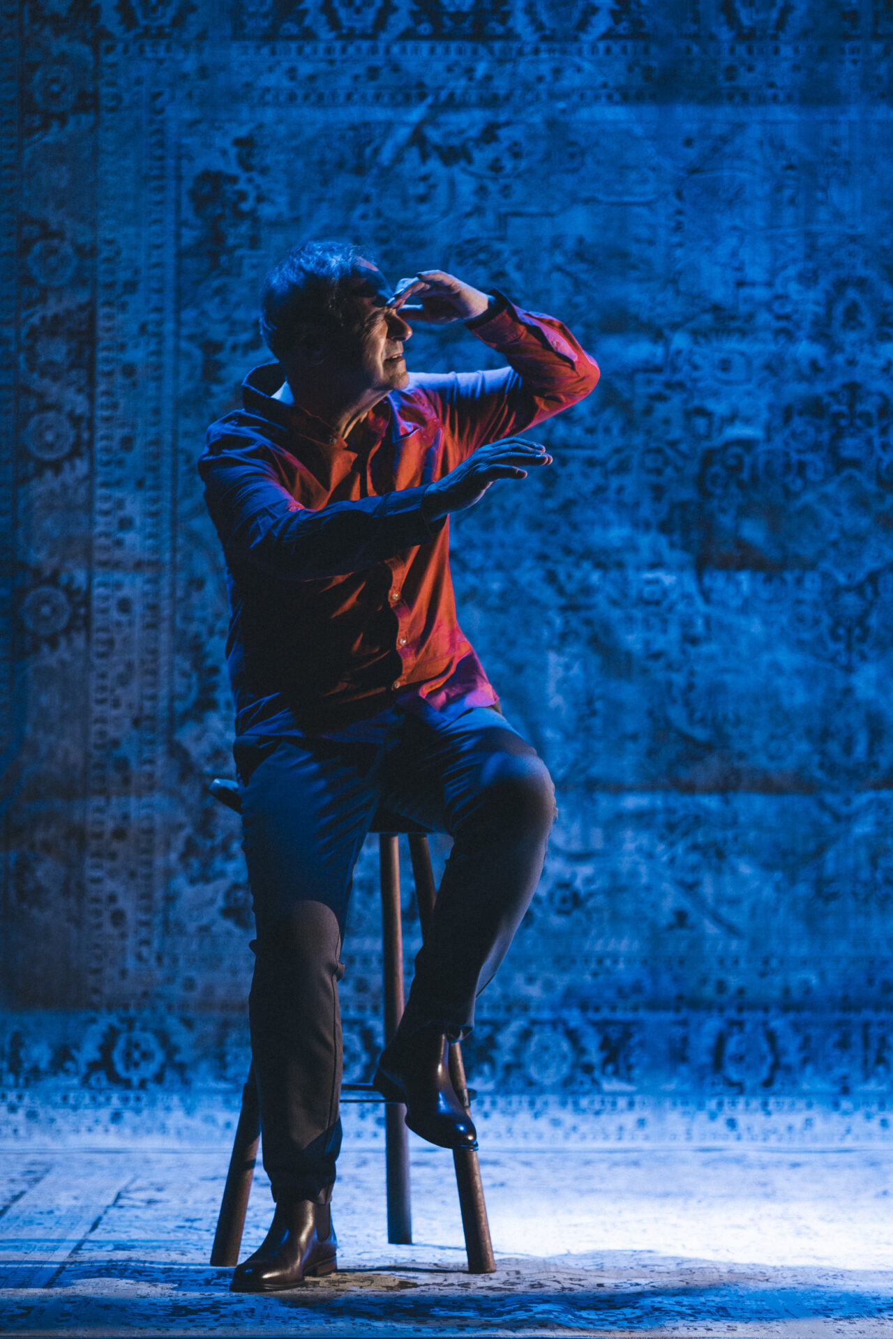 En mann som sitter på en krakk på scenen