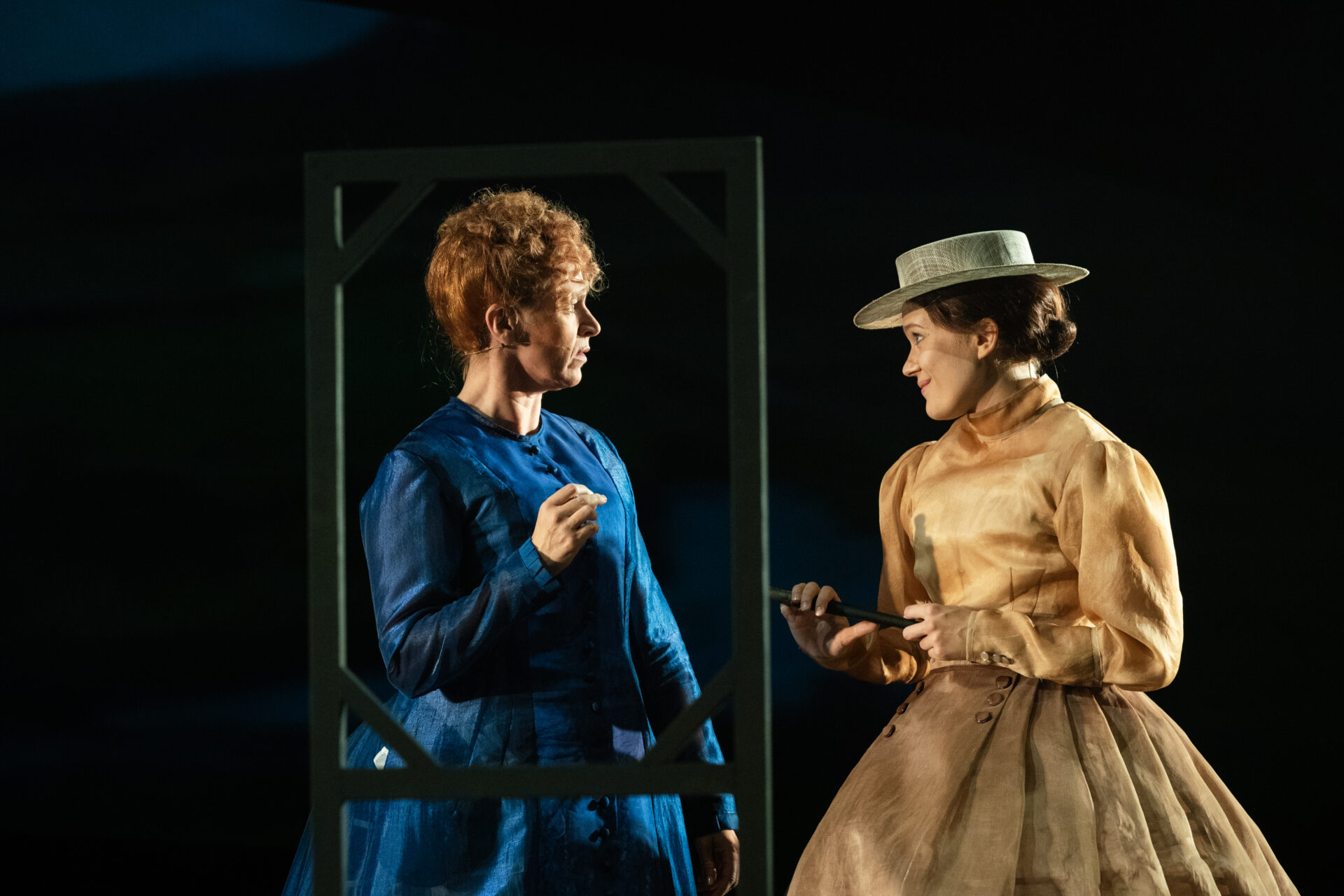 To festkledde kvinner på en scene, i stykket Alexander