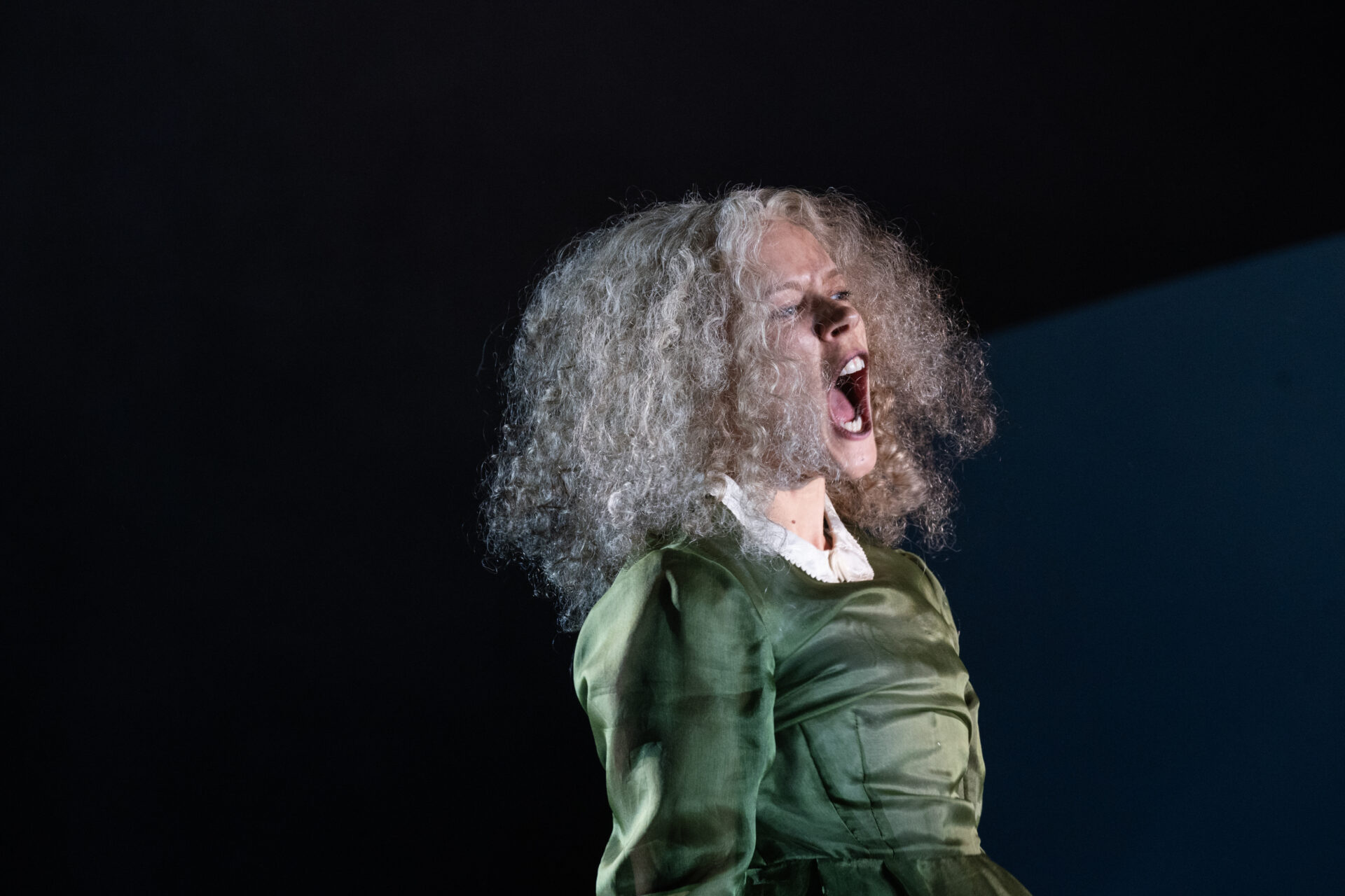 En kvinne med krøllete hår, som skriker ut