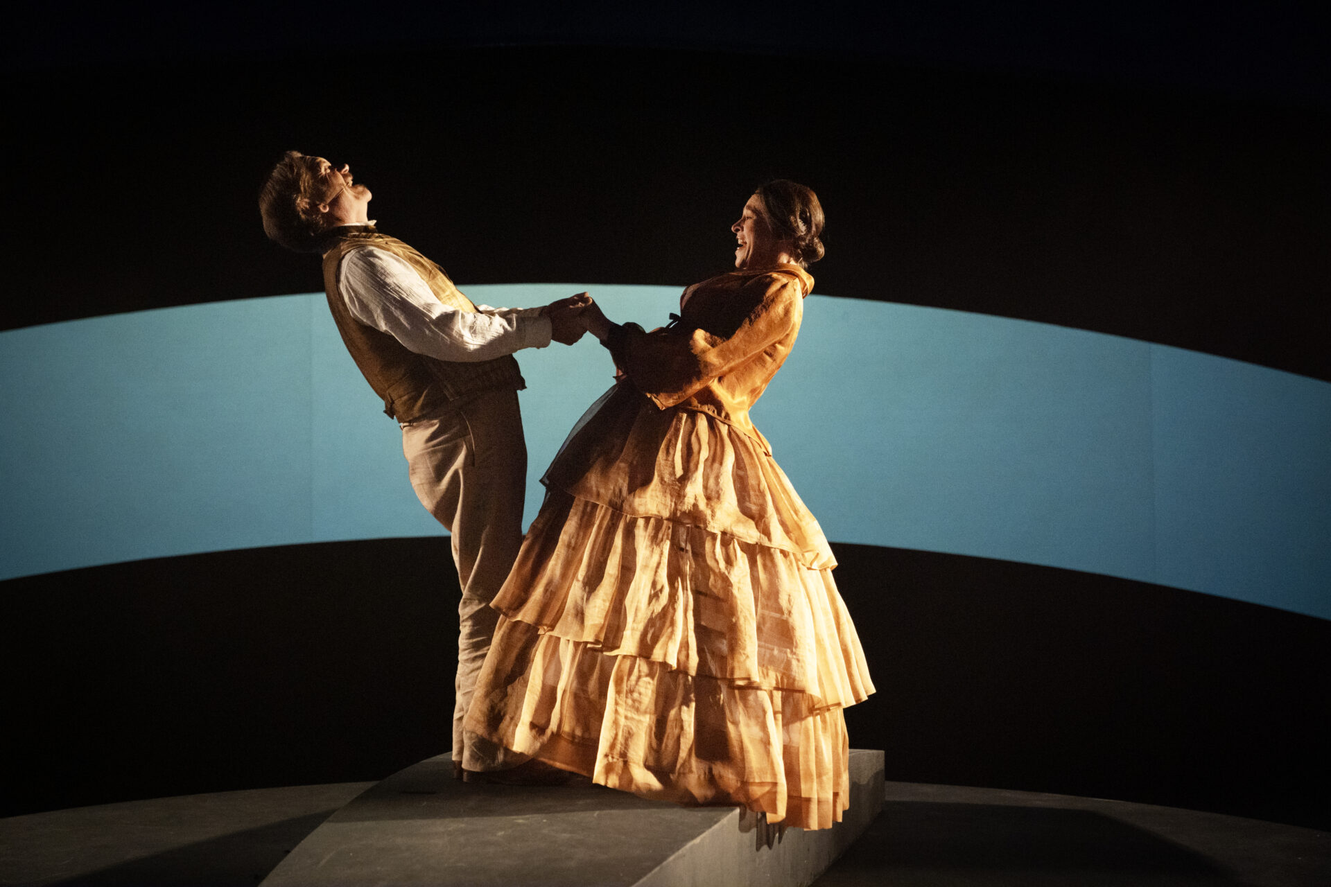 En festkledd mann og kvinne som holder hender og ler