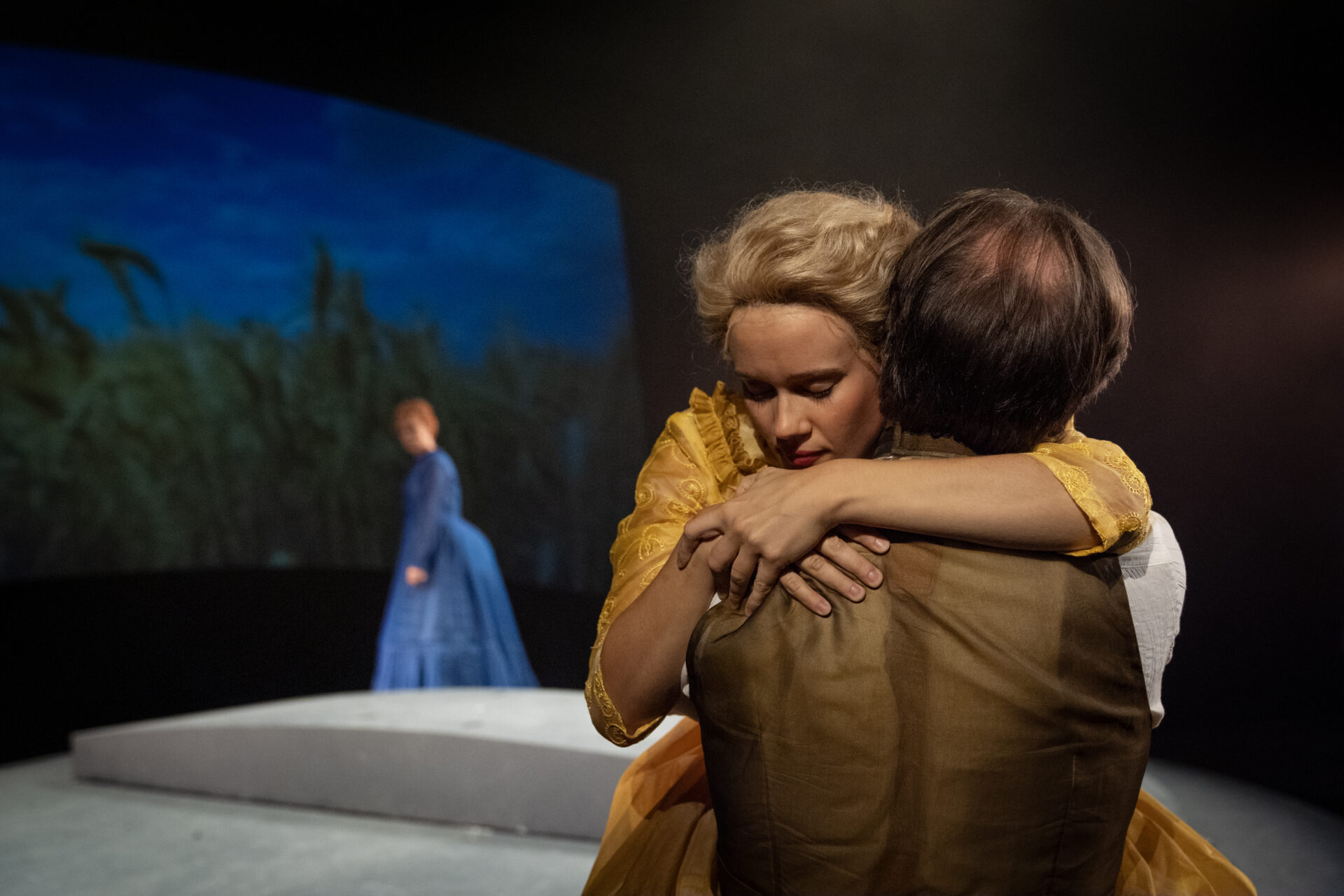 En mann og en kvinne som holder rundt hverandre på scenen, i stykket Alexander