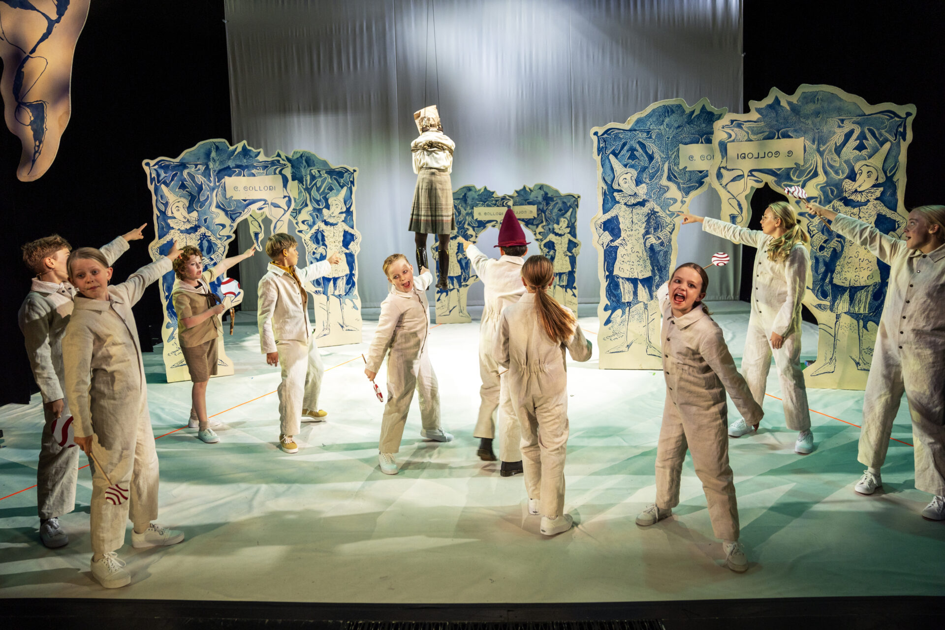 Mange barn peker på lærer som de har hengt opp i et tau.