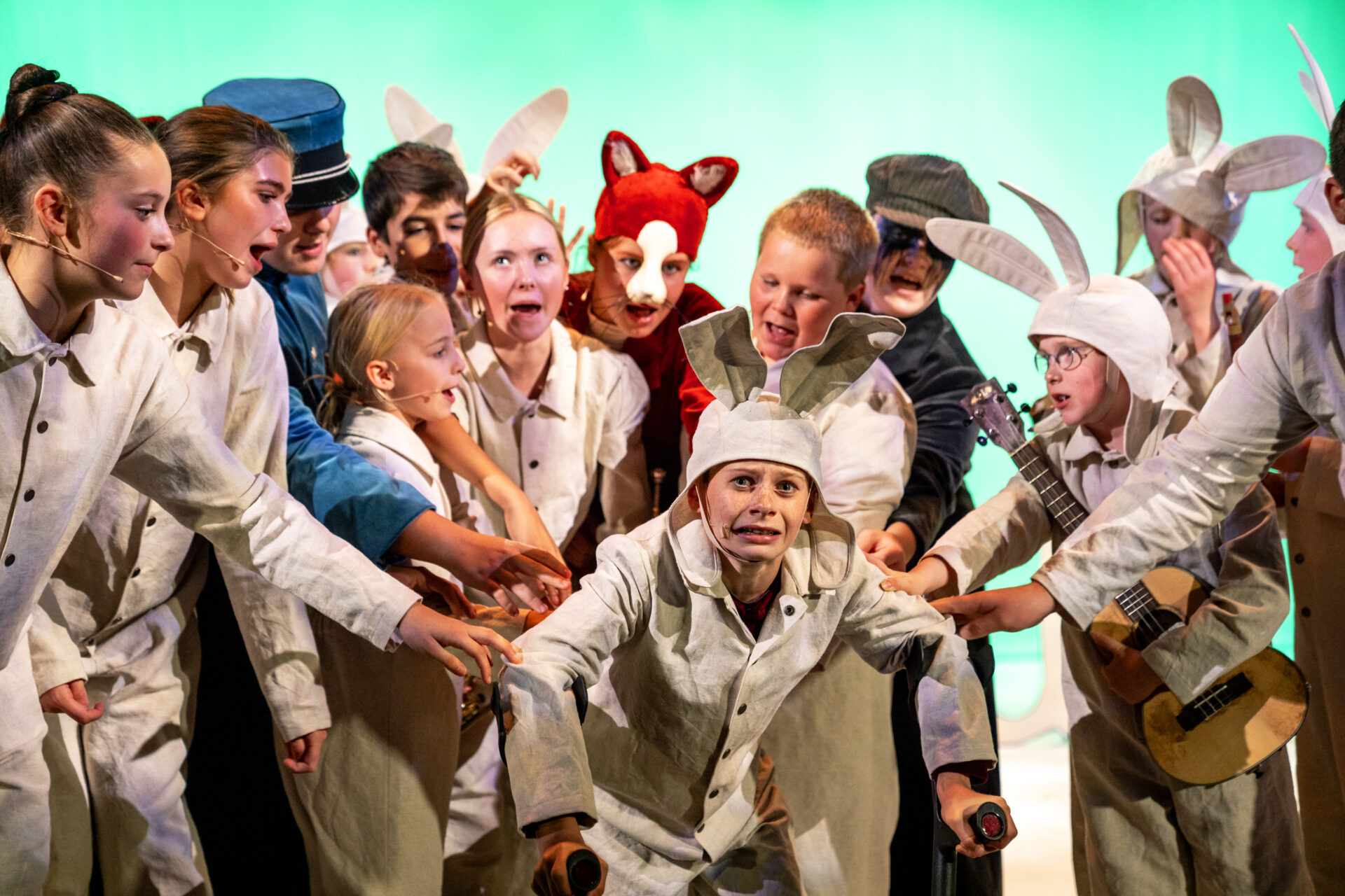 Pinocchio er blitt forvandlet til et esel og står i midten av en stor gruppe med ulige karakterer,