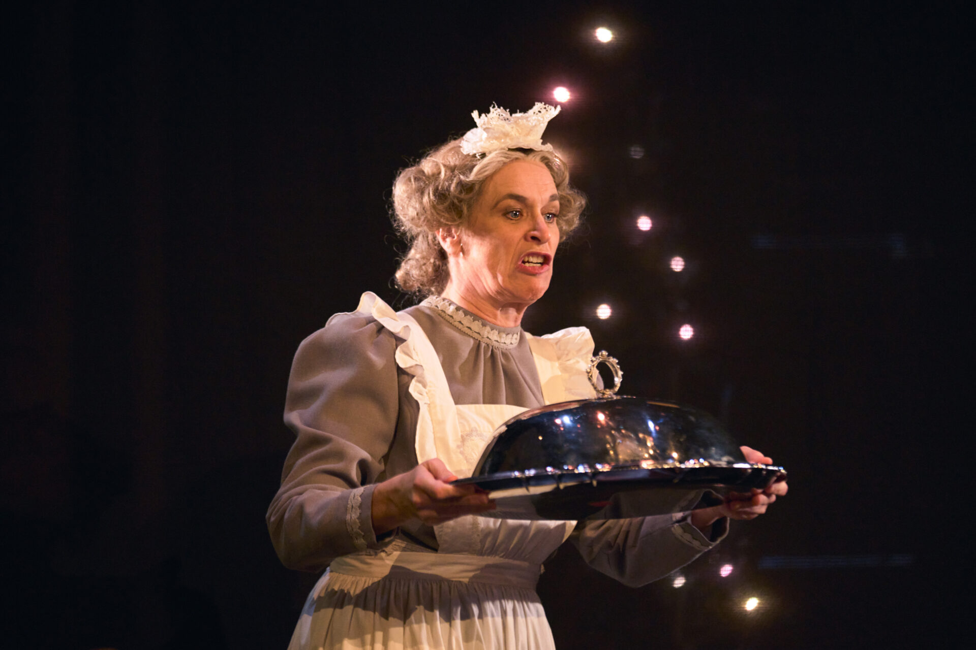 Kvinnelig skuespiller som holder et fat med mat - fra stykket julemiddag