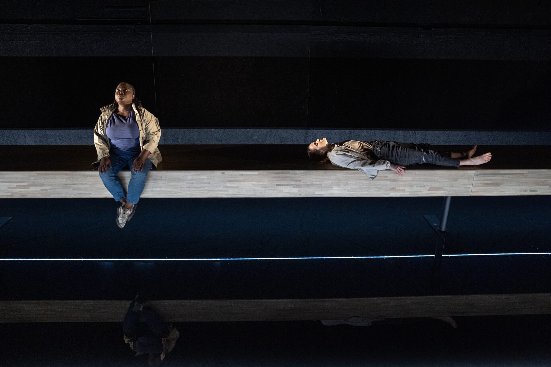 En skuespiller som ligger på ryggen, og en som sitter på scenekanten og titter opp - fra stykket Eg er vinden