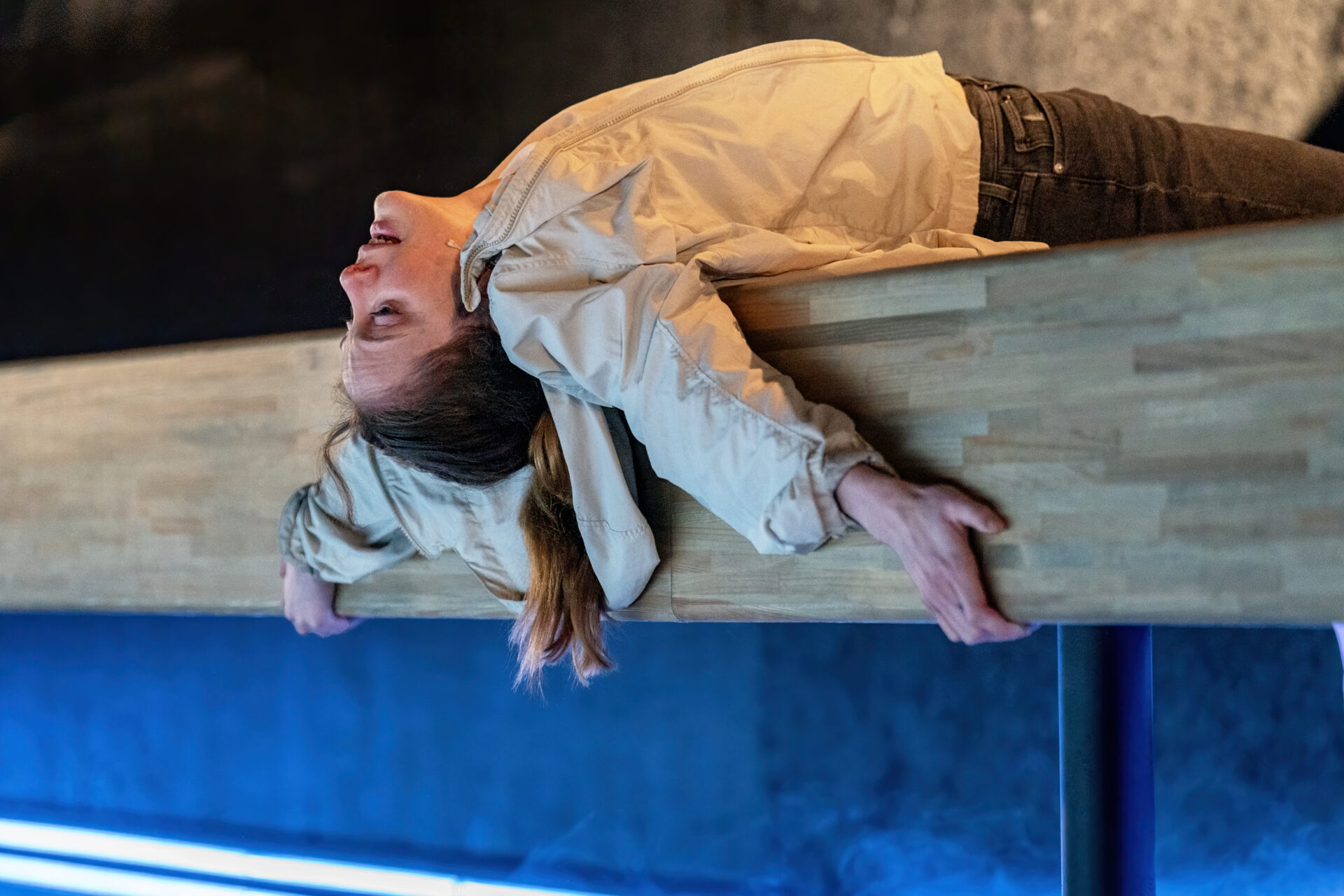 En skuespiller som ligger på ryggen og lener seg bakover scenekanten - fra stykket Eg er vinden