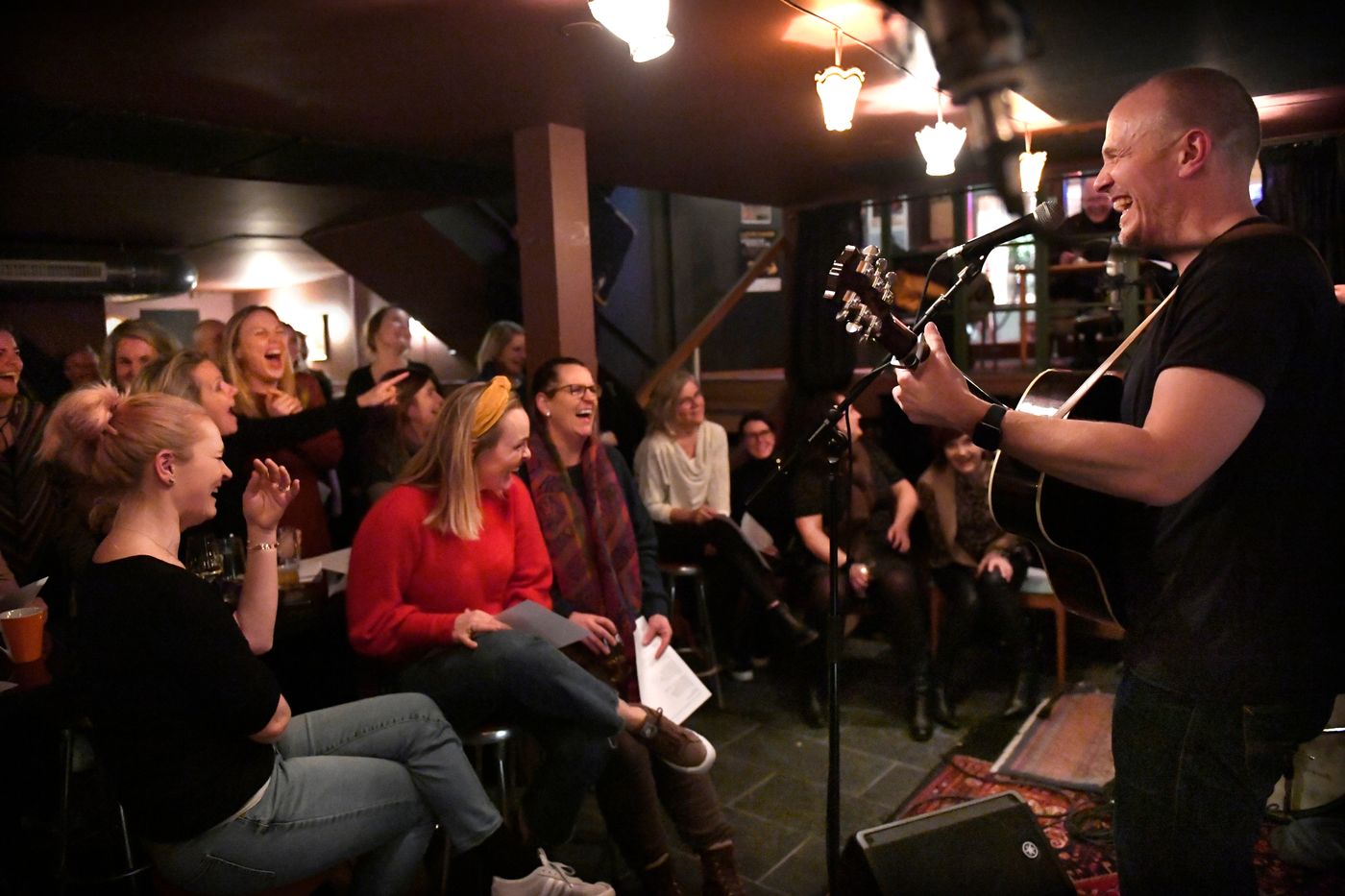 Mann med gitar som synger foran en forsamling