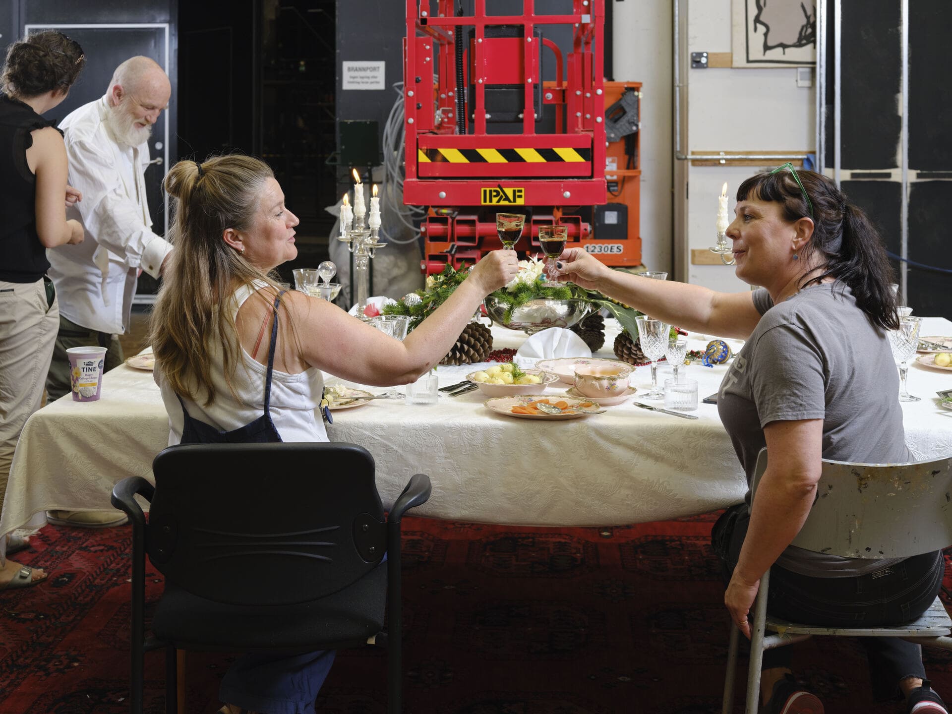 To kvinner sitter ved dekket bord og skåler.