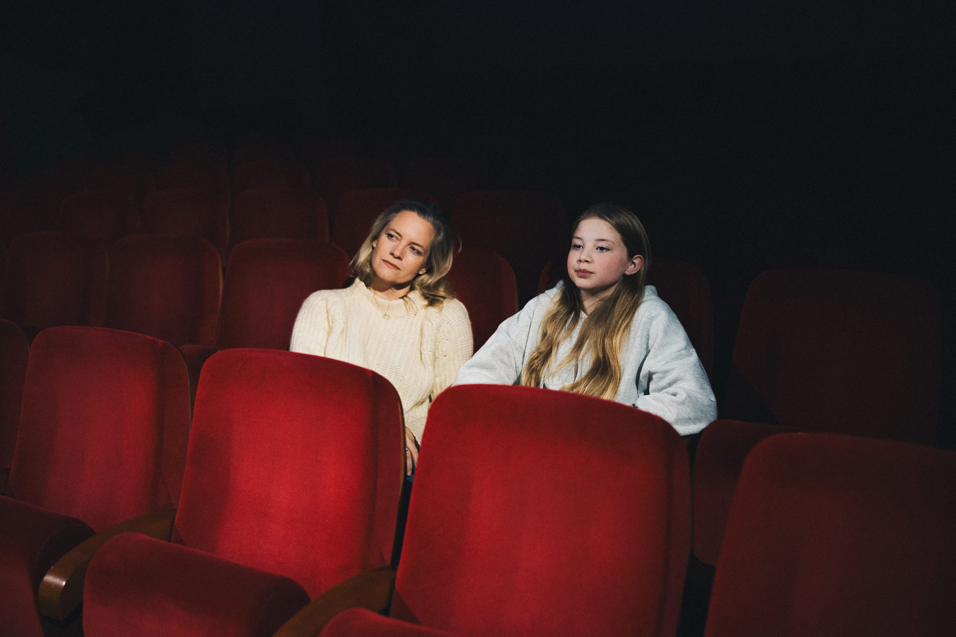Mor og datter sitter sammen i en teatersal.