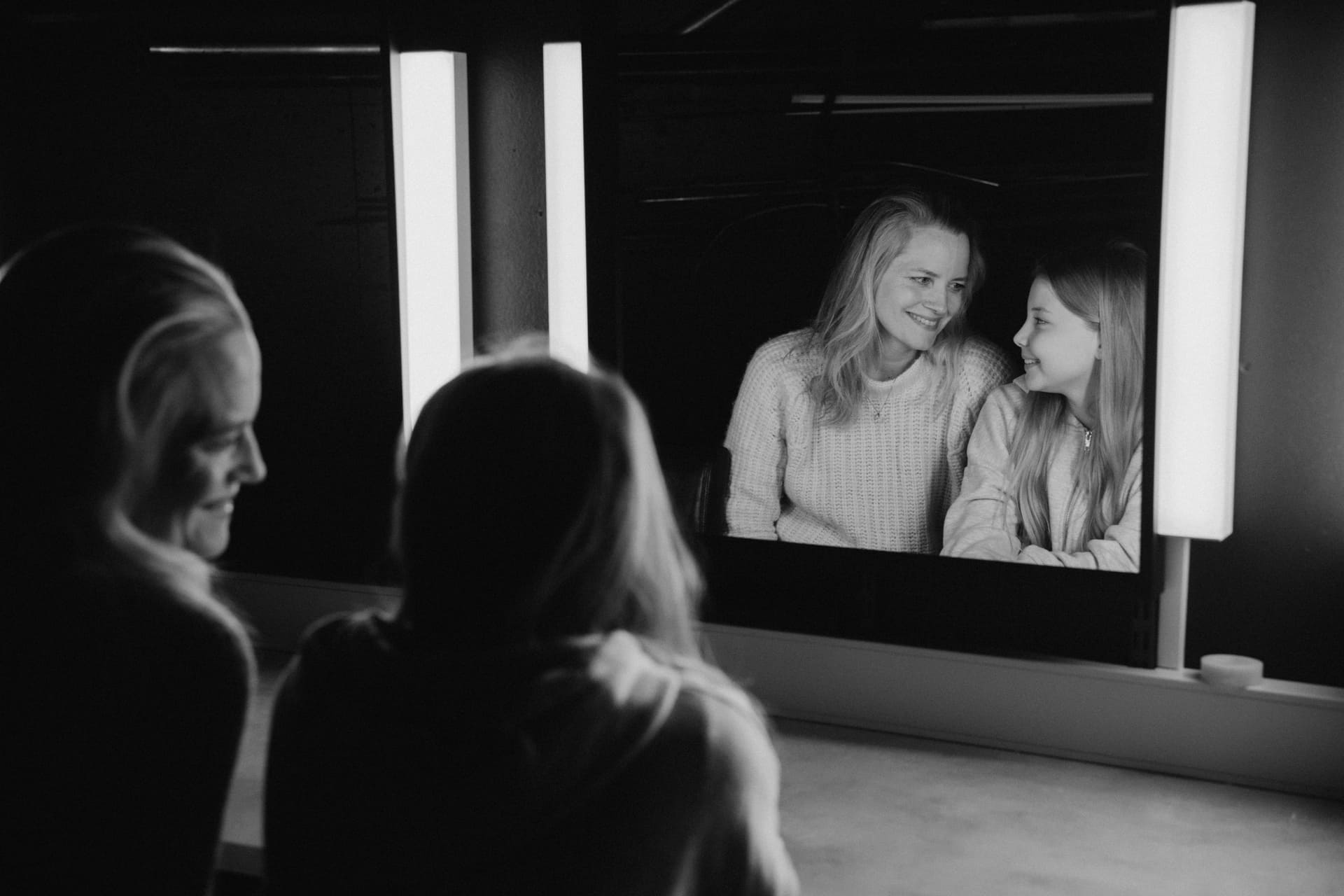 Mor og datter sitter foran et speil.