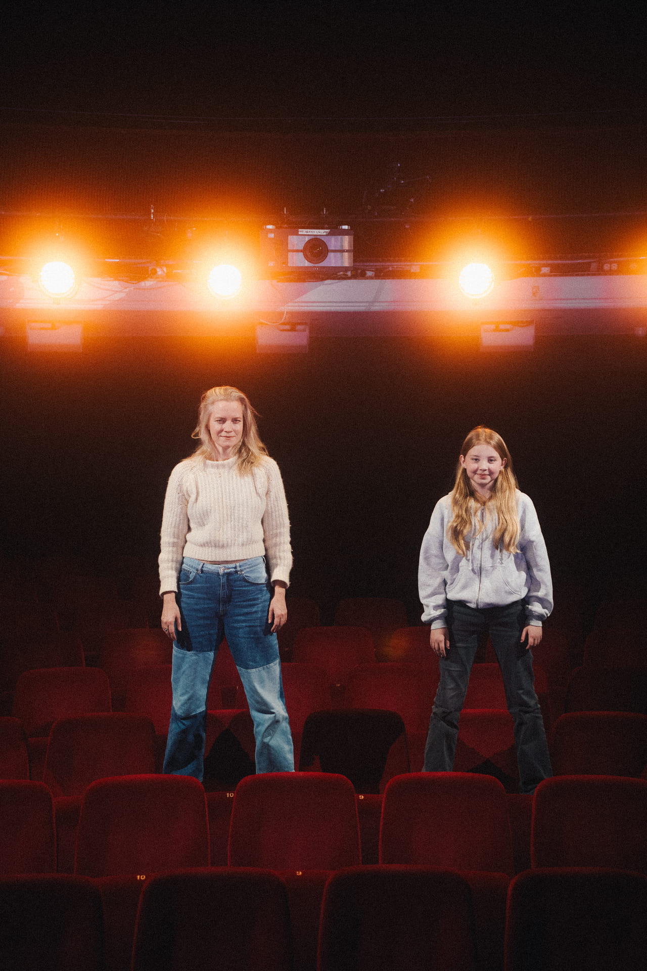 Mor og datter står oppreist blant setene i teatersalen.