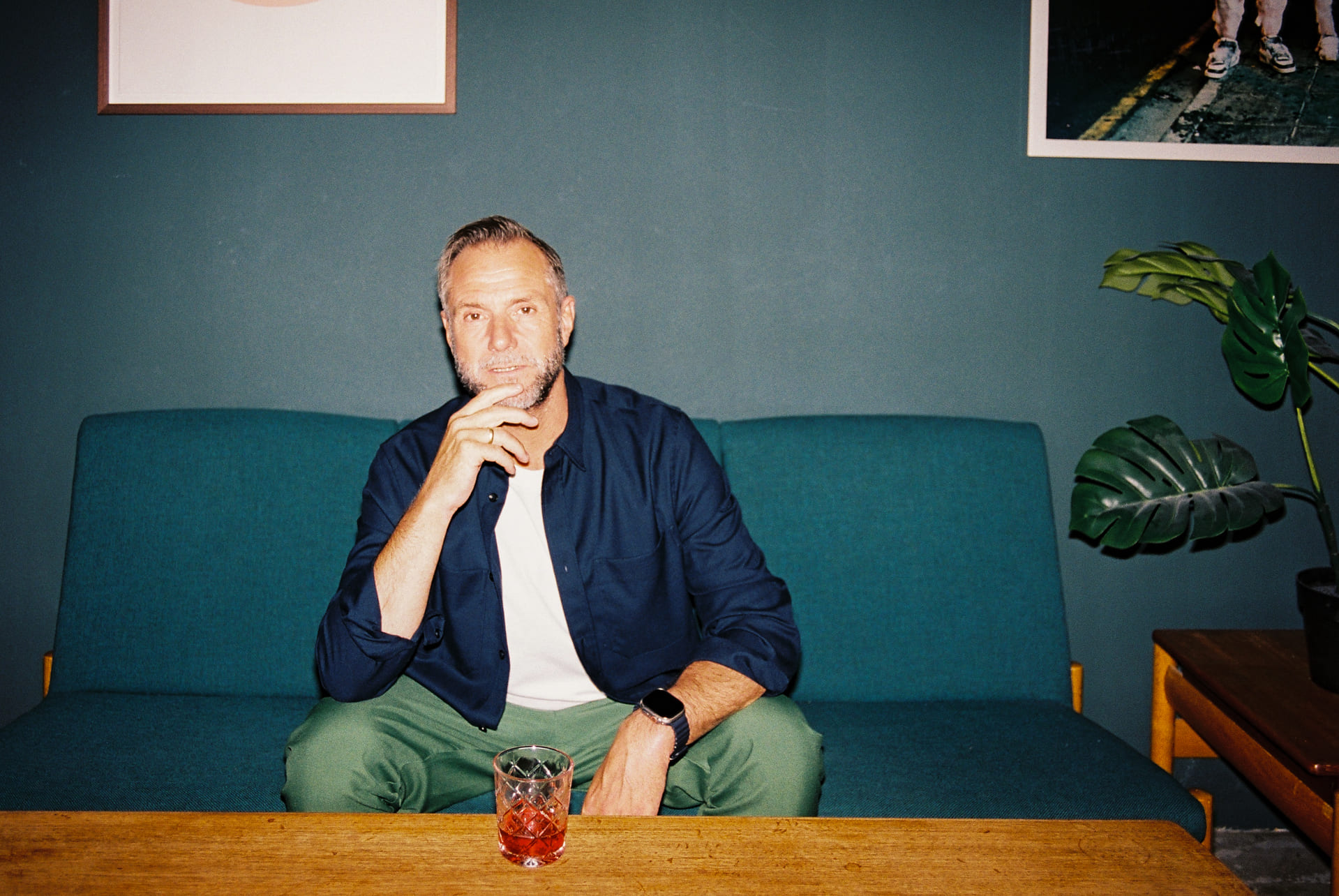Skuespiller Espen Reboli Bjerke sittende på blå sofa. På salongbordet foran står et glass whisky