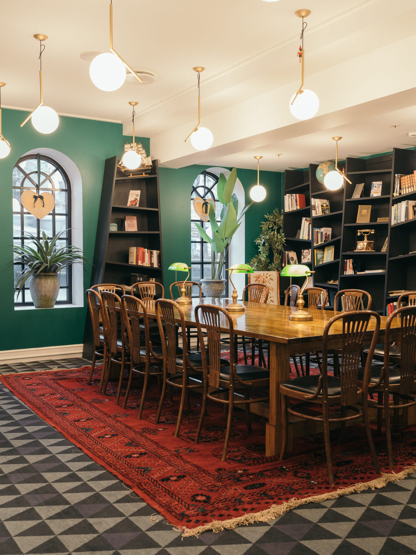 Et bord med leselamper står i et lunt rom. På veggene er det flere bokhyller fylt med bøker og ulike gjenstander.