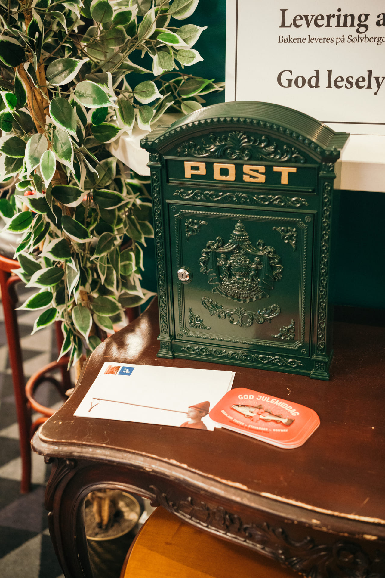 En historisk postkasse står på et bord. Foran ligger det en stabel brev.
