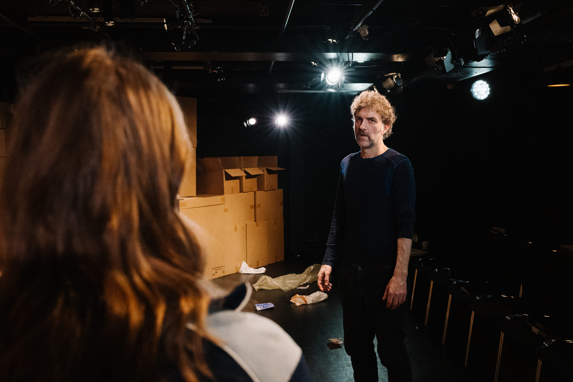 En mann står på scenen og ser mot en jente som har ryggen til kamera.