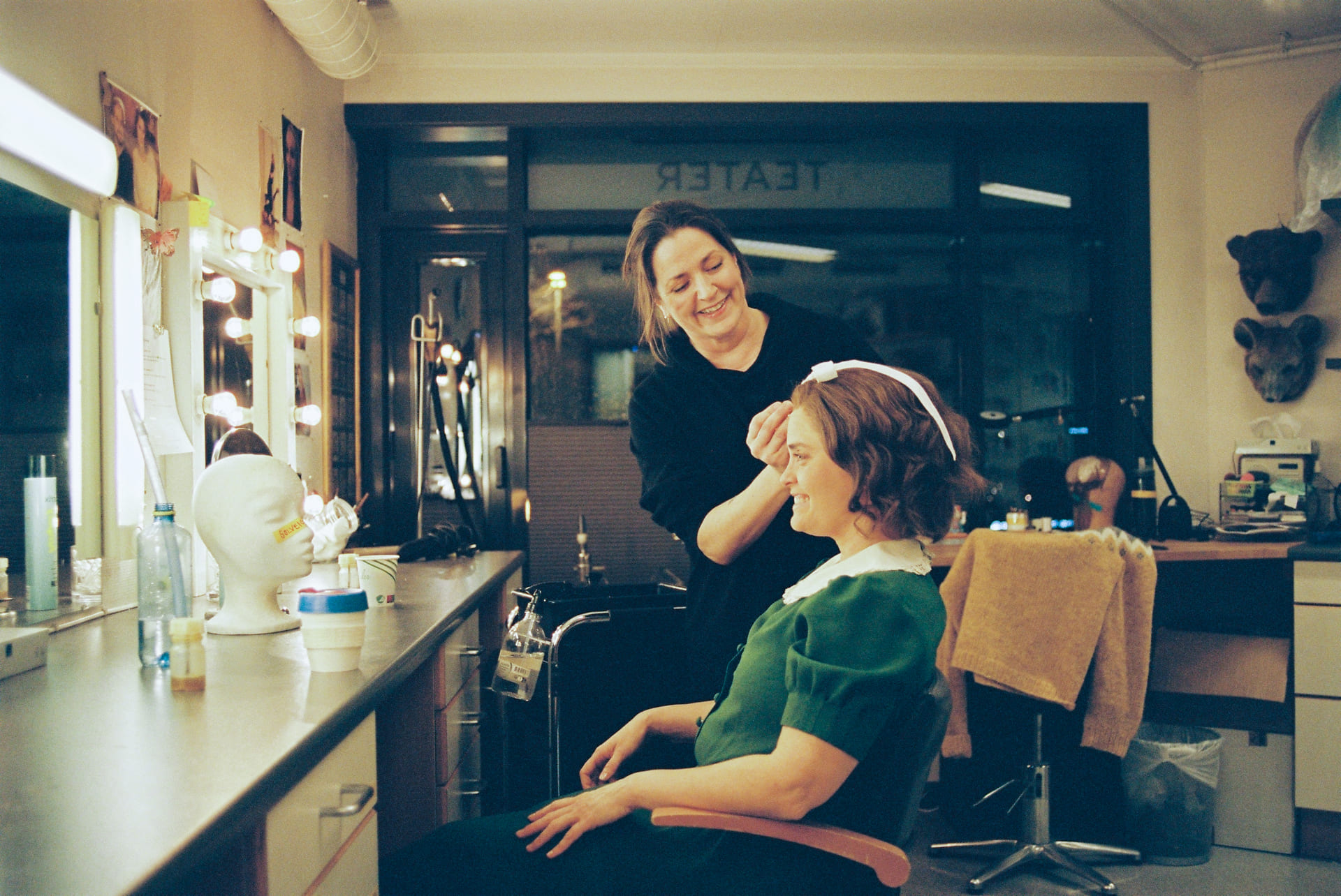 En kvinne ordner håret til en skuespiller i gammeldagse klær.