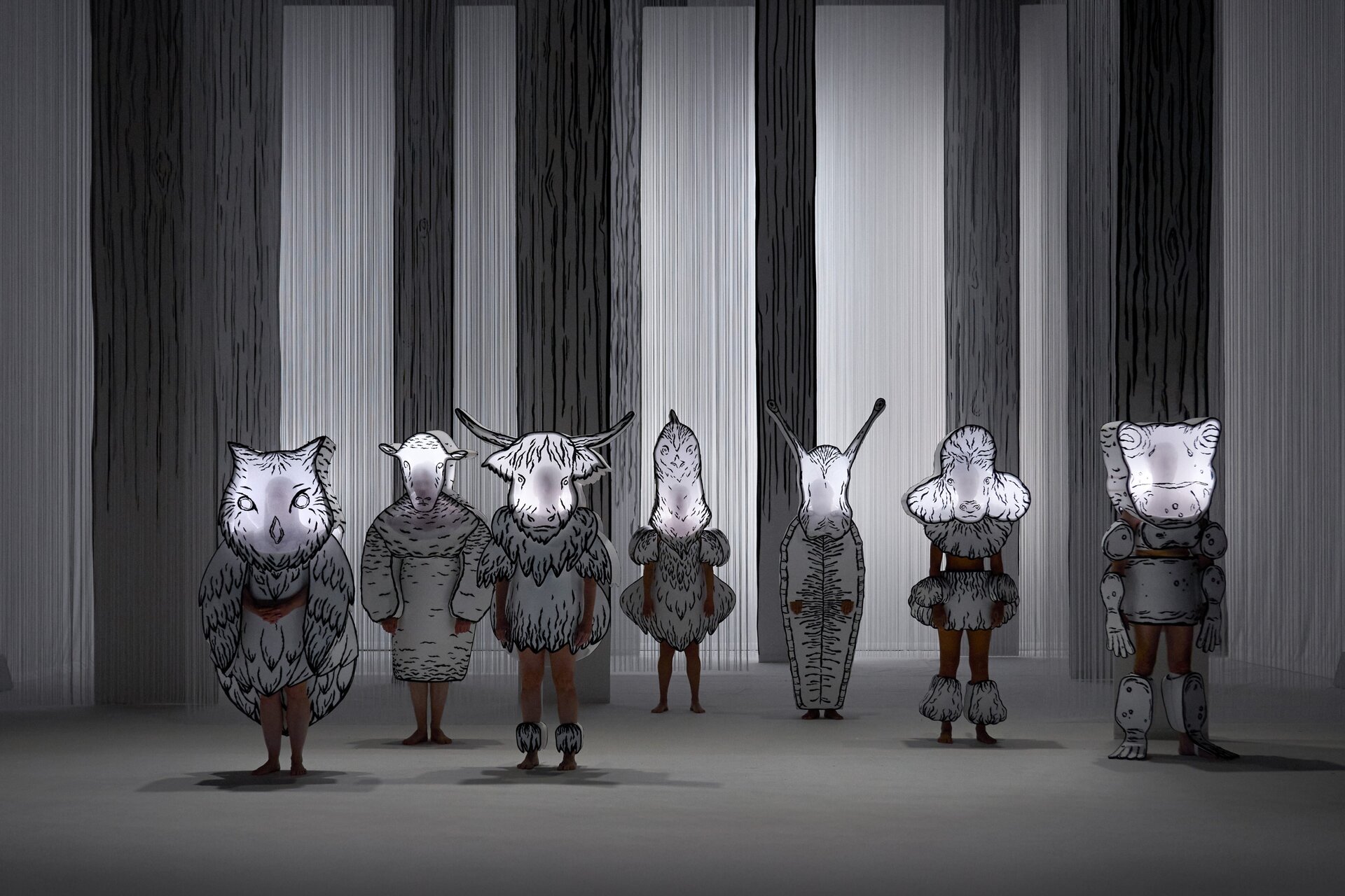 Syv skuespillere utkledd som sort-hvite kulltegnete dyr.