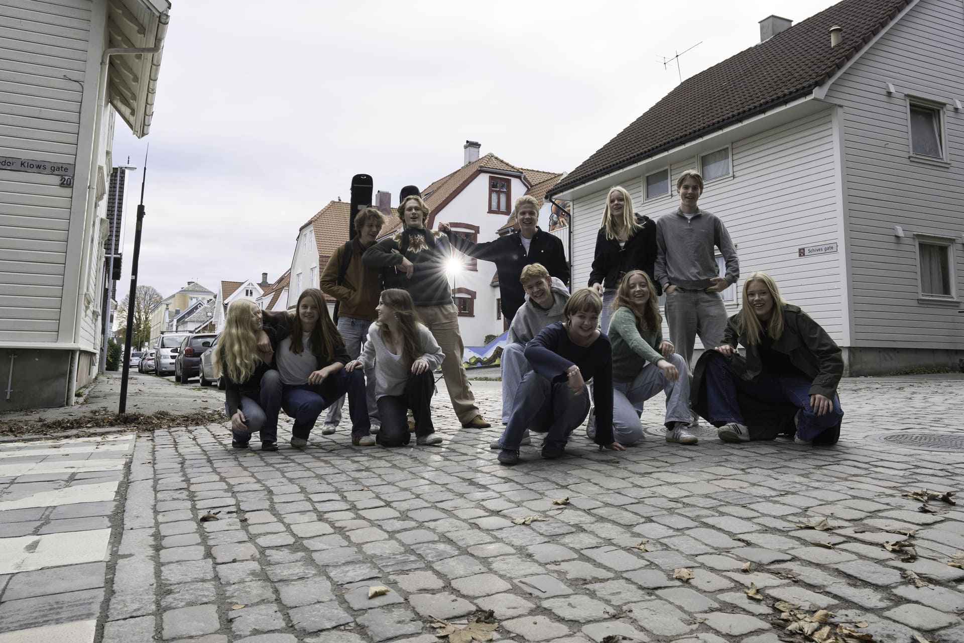 En gruppe ungdommer står midt i en gate og smiler mot kamera.